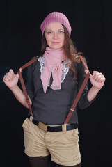 girl in a hat holding suspenders on a black background
