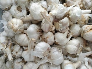Close-up of white garlic bulbs in a pile, showing texture and natural forms. Ideal for culinary, health, or agricultural-themed visual content