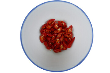 Vibrant red chili pepper slices sit within crisp white bowl, ready as spicy ingredient for variety of hot cuisine. This fresh food delivers pungent flavor