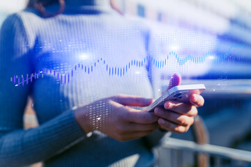 Young woman using mobile phone, financial charts and global map behind.