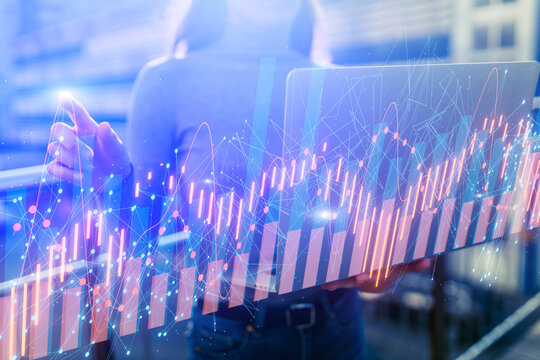 Female entrepreneur holding laptop, stock trading graphs - Powered by Adobe