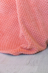 Close-up photo of a soft pink blanket with textured knitting and a velvety surface. Warm and cozy textiles, ideal for home interiors, relaxation and decor. The fabric looks delicate and pleasant to