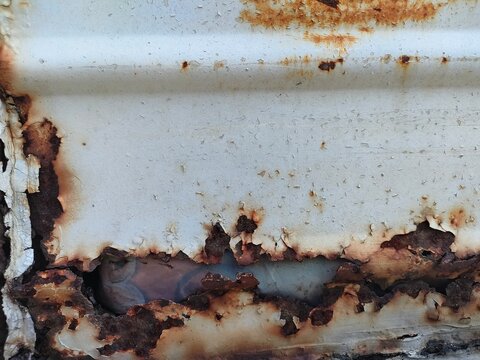 Close-up of heavily rusted and peeling metal surface, showing corrosion. Ideal for texture, decay, industrial, or weathered-themed visual content