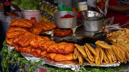 A table is filled with a variety of Mexican food, including tacos, tortillas, and other dishes. Historic center of Queretaro City, decorations and traditions to celebrate Mexico's Independence Day, co