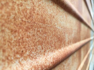 Close-up of rusted corrugated metal with diagonal ridges and textured oxidation. Ideal for industrial, grunge, decay, or background themes in design and photography.