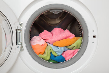 White opened washing machine full of colorful microfiber cleaning rags. Closeup. Front view. © fotoduets
