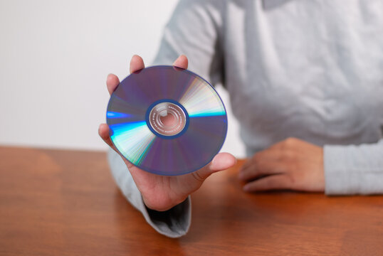 User holding cd indoor setting technology content minimalist environment close-up view digital media concept