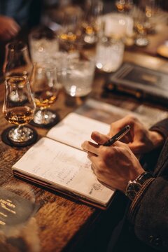 A guest holding a tasting notebook They jot down notes after each sip The mood feels reflective and curious