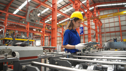 Young female worker inspecting machines on a production line