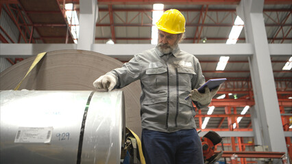 Senior experienced technician checking large machine on a production line at an industrial factory