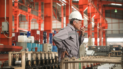 Industrial worker in protective gear experiencing back pain while working on factory machinery