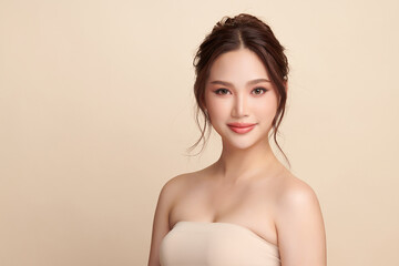 Obraz premium A beautiful young Asian woman with clean, fresh skin against a beige background. Skincare, facial treatment, cosmetology, beauty, and spa. An elegant portrait of an Asian woman.