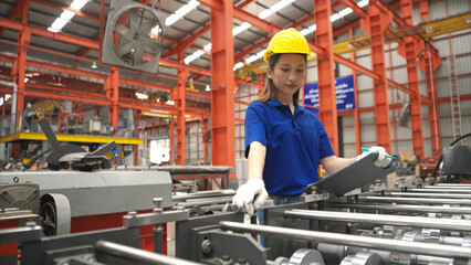 Young female worker inspecting machines on a production line