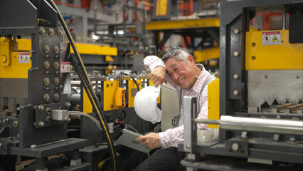Senior experienced technician checking large machine on a production line