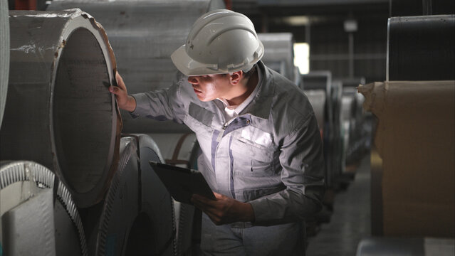 Industrial worker inspecting inside a large metal tube in a factory