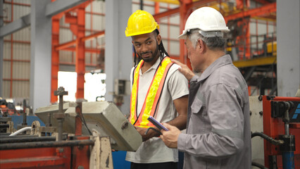 Senior engineers and young man workers are talking and inspecting machines on a production line