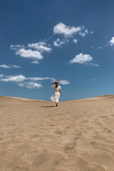 Woman Running on Sand Dunes Under Blue Sky