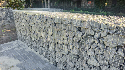 Stone fence construction. Mesh base with stones inside. Open space design