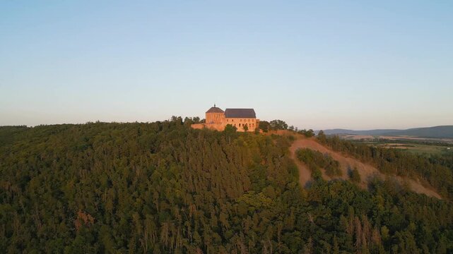Explore Tocnik Castle situated on a hill, showcasing its medieval architecture against a stunning sunset backdrop. Experience the tranquil evening atmosphere in Czechia.