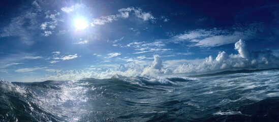 Ocean panorama Bright sun, blue sky, fluffy clouds, and choppy waves