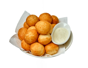 Golden baursaks on a paper towel with kaymak in a white bowl — a cozy presentation of a traditional Central Asian snack.