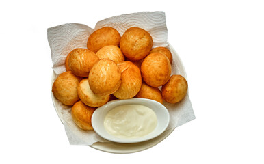 Golden baursaks on a paper towel with kaymak in a white bowl — a cozy presentation of a traditional Central Asian snack.