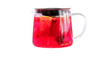 Berry tea with lemon and fruit pieces in a glass pitcher with black lid — a rich infusion with vibrant visual appeal.