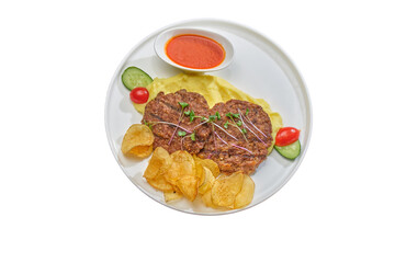Grilled beef patties with microgreens, mashed potatoes, chips, sauce, and fresh vegetables — a balanced dish on a white plate.