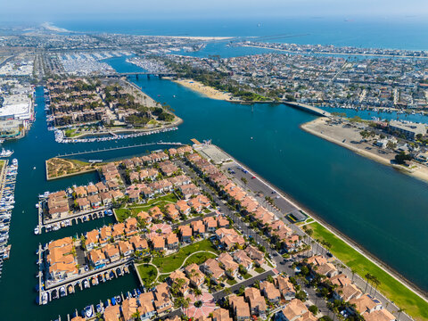 Drone view of upscale waterfront homes and narrow canals lined with docked yachts and boats in Long Beach, California, showcasing premium real estate and marina lifestyle