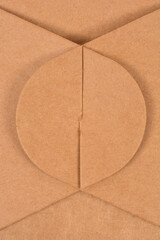 An abstract view of a detail on a brown cardboard package, with visible folded corners and a circular cutout