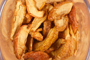 A close-up view shows a pile of wrinkled dried apples in a plastic container