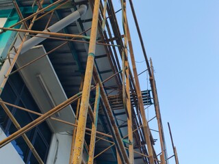 Upward view of steel scaffolding at a building construction site during daytime, set against a clear blue sky. Ideal for construction, engineering, or industrial-themed visual content.