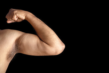 Close-Up of Flexed Bicep Connoting Strength and Fitness on a Black Background