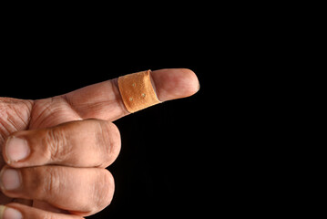 Injured Finger Covered With Band-Aid on a Dark Background