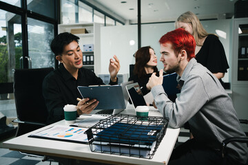 Four colleagues engage in a collaborative office meeting, using laptops, tablets, and documents to brainstorm ideas, discuss strategies,share insights, fostering teamwork, productivity, professional