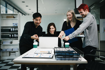Four colleagues engage in a collaborative office meeting, using laptops, tablets, and documents to brainstorm ideas, discuss strategies,share insights, fostering teamwork, productivity, professional