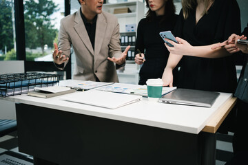 Four colleagues engage in a collaborative office meeting, using laptops, tablets, and documents to brainstorm ideas, discuss strategies,share insights, fostering teamwork, productivity, professional