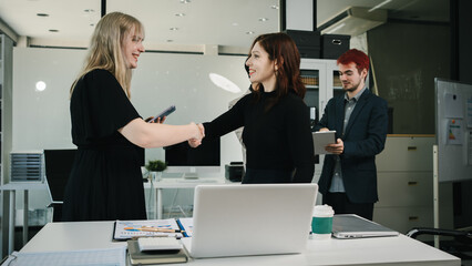 Four colleagues engage in a collaborative office meeting, using laptops, tablets, and documents to brainstorm ideas, discuss strategies,share insights, fostering teamwork, productivity, professional