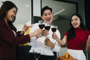 Four cheerful friends celebrate together in an office party, enjoying delicious food, fried chicken, pizza, salad, wine. Surrounded by balloons and laughter, they share happiness, marking   year-end