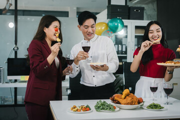 Four cheerful friends celebrate together in an office party, enjoying delicious food, fried chicken, pizza, salad, wine. Surrounded by balloons and laughter, they share happiness, marking   year-end
