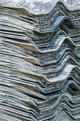 Old, weathered, black, dirty roof tiles stacked in layers.