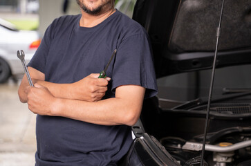 An Asian man and his tools are maintaining his car by himself.