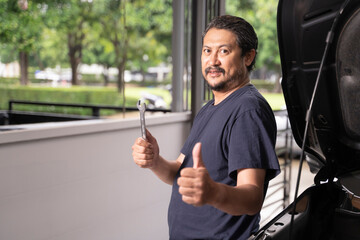 An Asian man and his tools are maintaining his car by himself.