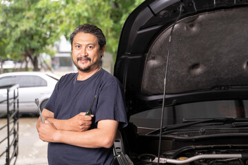 An Asian man and his tools are maintaining his car by himself.