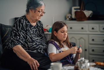 Grandmother teaching granddaughter knitting at home