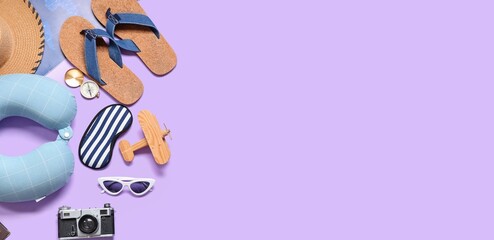 Travel pillow, photo camera, compass and beach accessories on lilac background with space for text