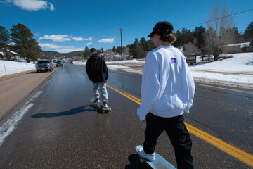 teenagers are skating down snowy road showcasing their skills with impressive tricks against ultrabright blue sky