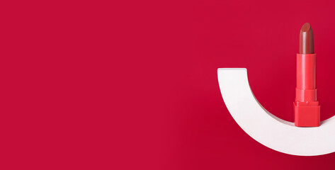 Decorative plaster podium and lipstick on red background