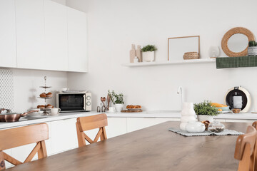 Interior of modern kitchen with white counters, table and shelf