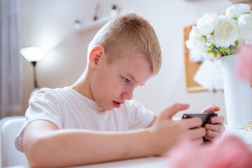 A boy with hearing aids engages with a smartphone, playing mobile games with focused enjoyment....